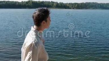 阳光明媚的夏日，穿着白色衬衫的媚兰男孩在湖边散步